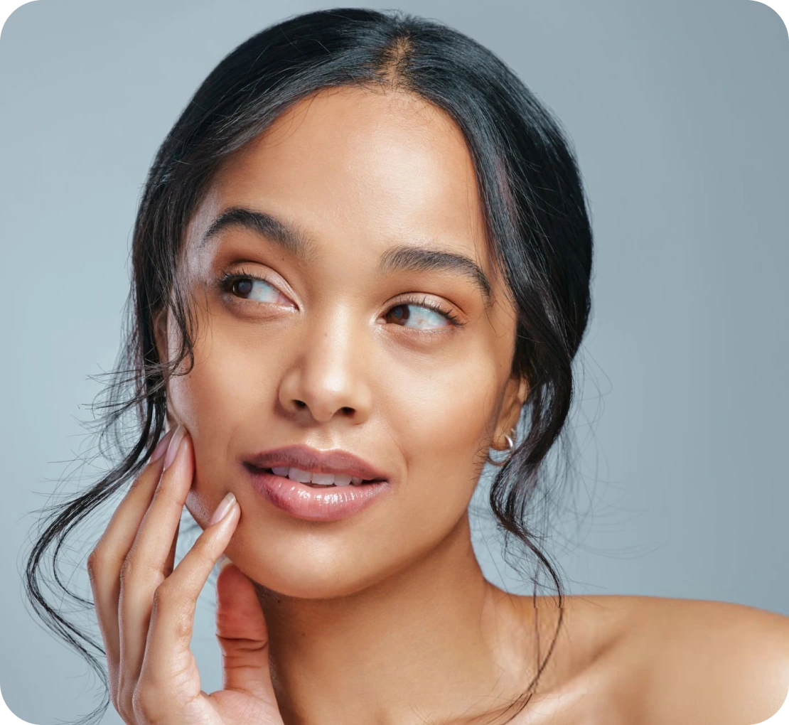 Woman touching her cheek against a neutral background